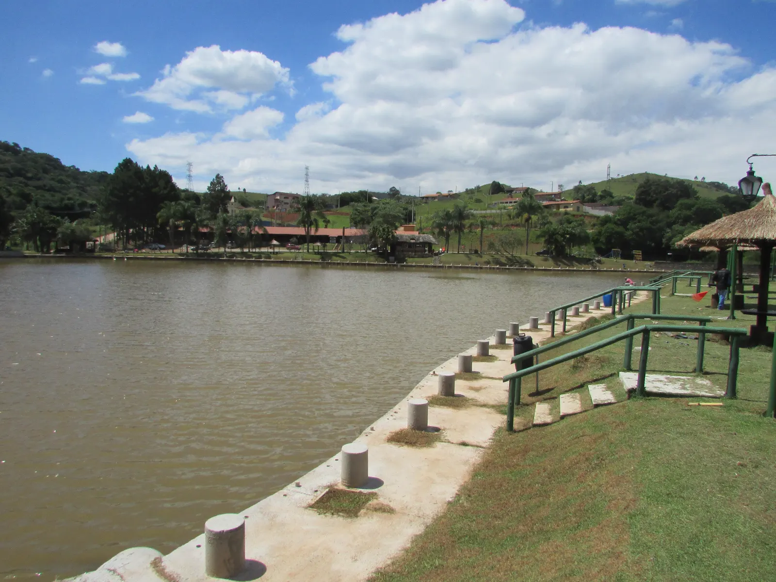 Margem do lago com pesqueiros e corrimão verde