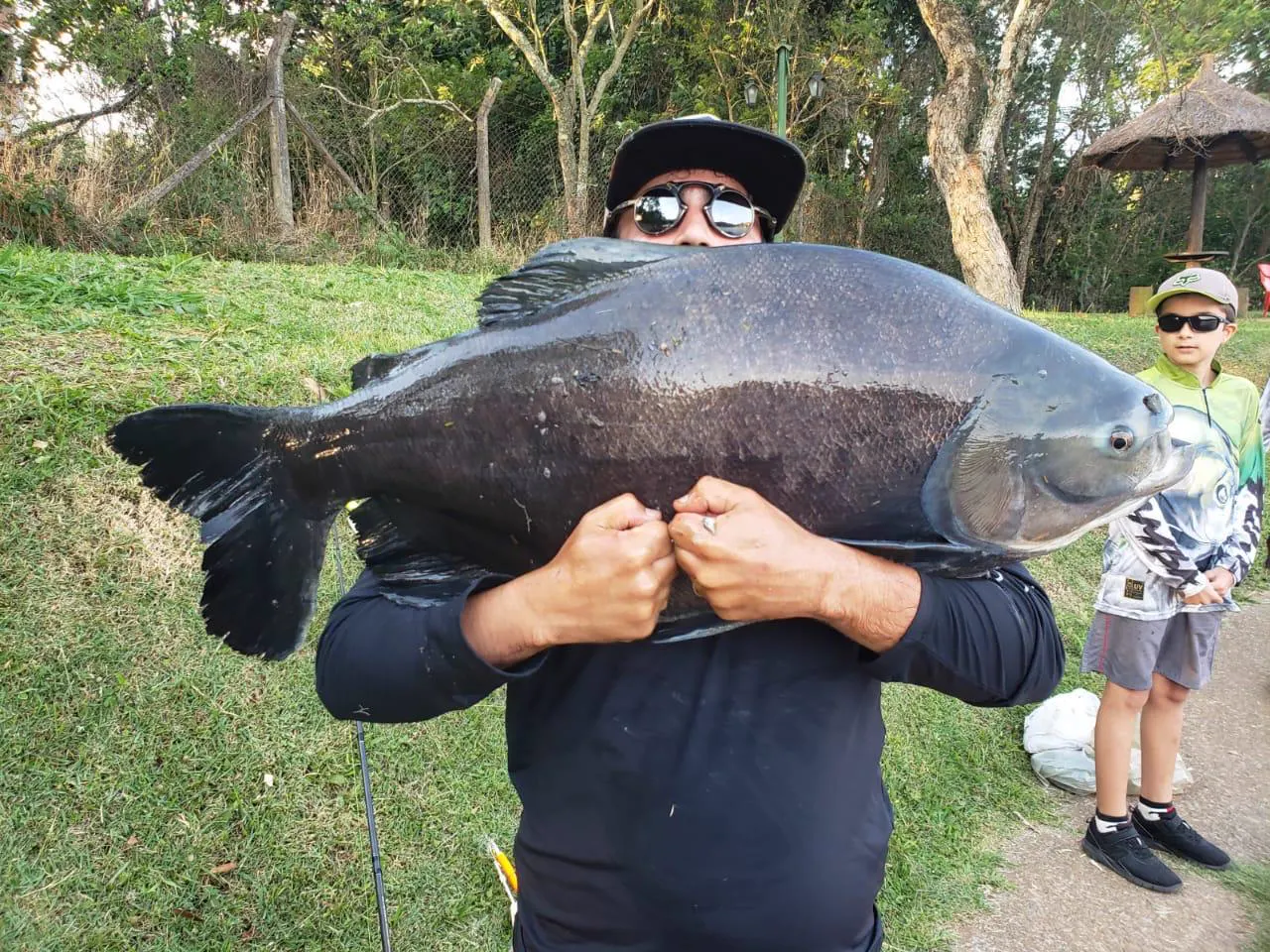 Pai segura um tambaqui enorme ao lado do filho