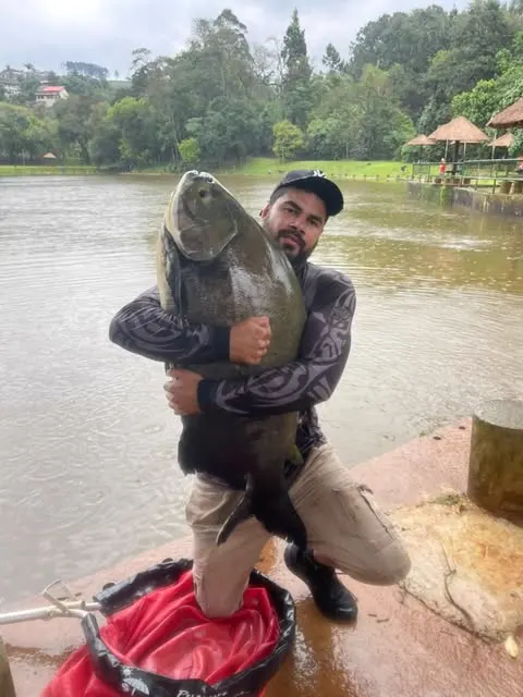 Pescador em pé no píer segurando um peixe