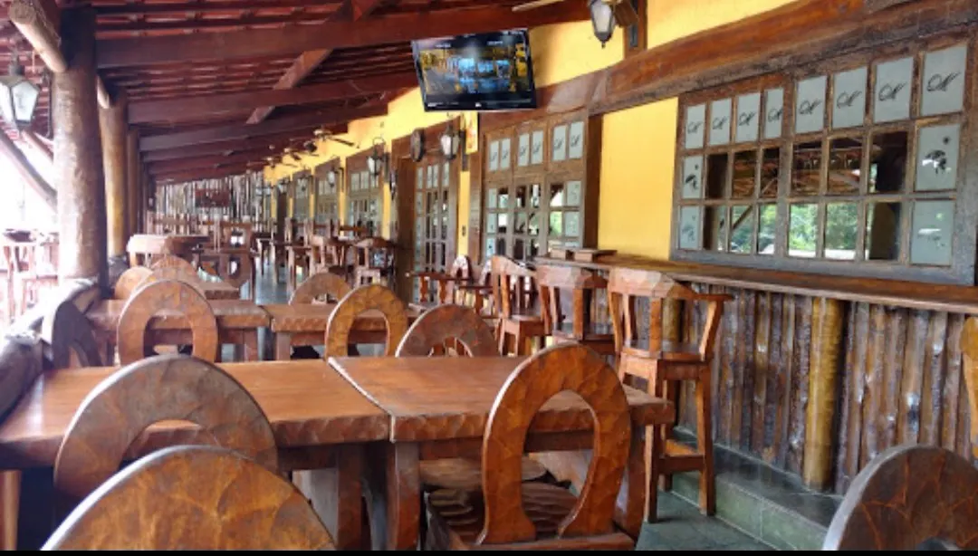 Salão interno com mesas e cadeiras de madeira rústica