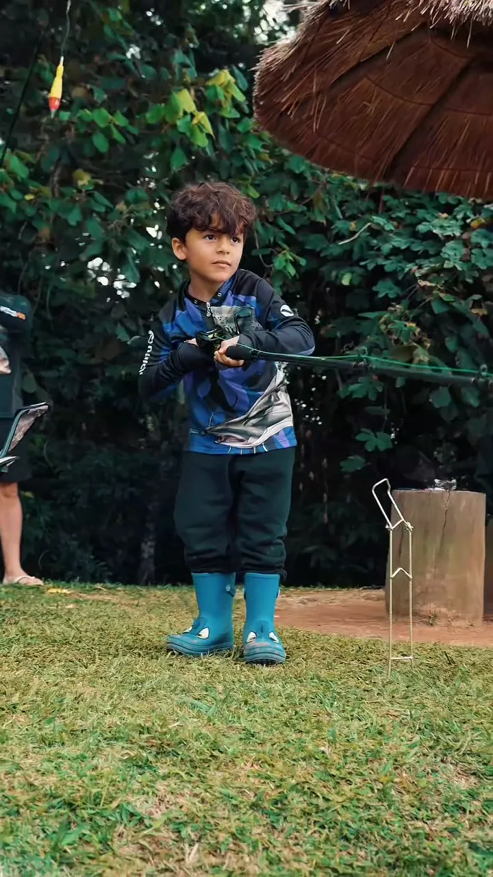 Criança pescando de bota azul na margem